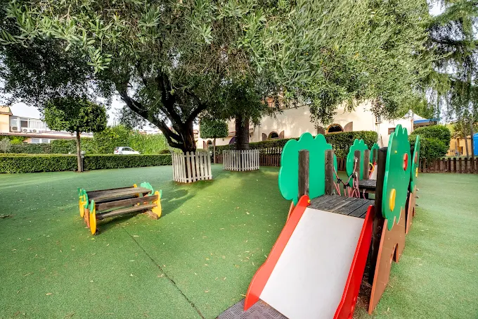 Parco giochi con scivolo a casetta e ulivo secolare